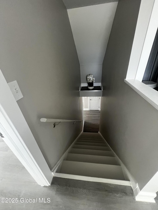 stairs featuring baseboards and vaulted ceiling