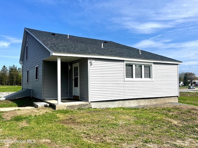 back of house featuring roof with shingles