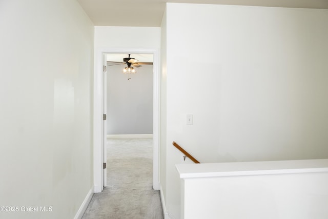 hall featuring an upstairs landing, light colored carpet, and baseboards