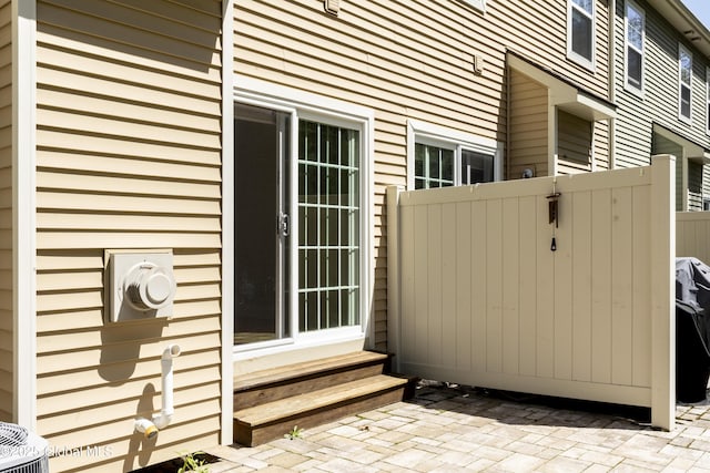 view of home's exterior featuring fence, entry steps, a gate, central AC unit, and a patio