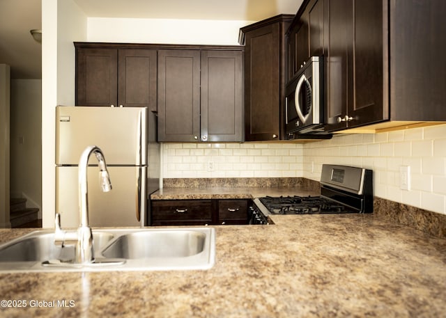 kitchen featuring stainless steel appliances, a sink, dark brown cabinets, and tasteful backsplash