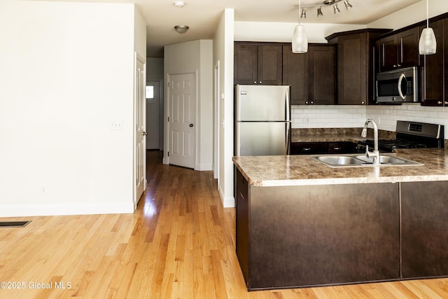 kitchen featuring stainless steel appliances, a sink, dark brown cabinets, light wood-type flooring, and a peninsula