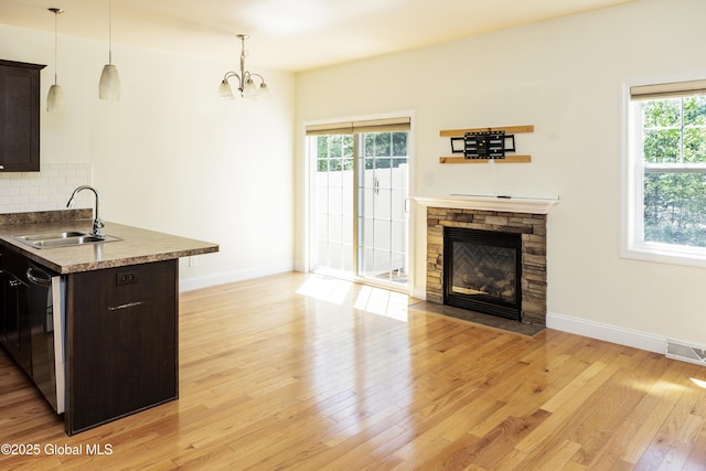 kitchen featuring a sink, dark brown cabinets, light wood-style floors, a fireplace, and a chandelier
