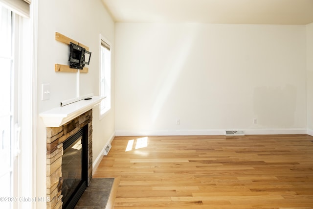 unfurnished living room with a fireplace, light wood finished floors, and baseboards