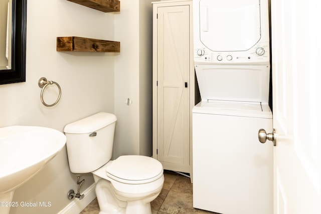 half bath featuring stacked washer and clothes dryer and toilet