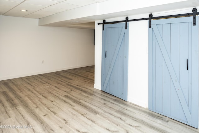 basement with a barn door, wood finished floors, baseboards, and recessed lighting