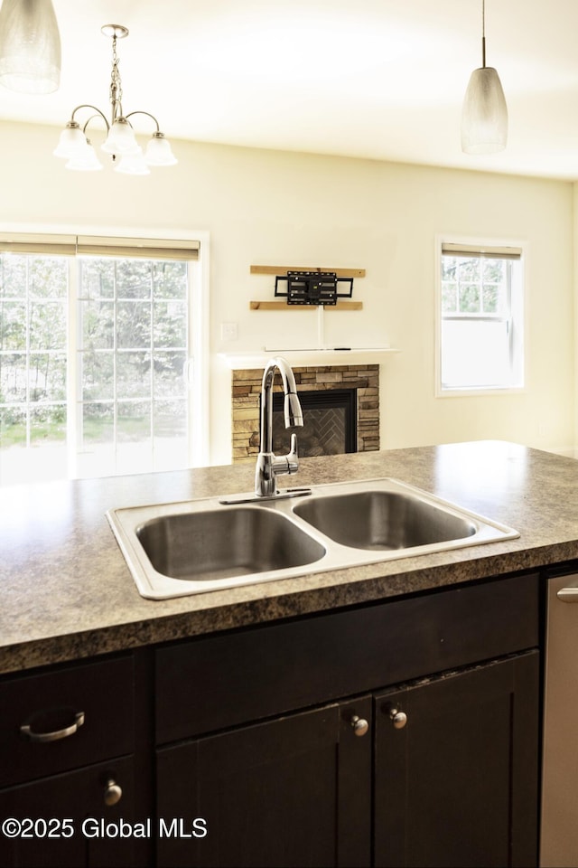 kitchen featuring a sink, stainless steel dishwasher, pendant lighting, and a chandelier