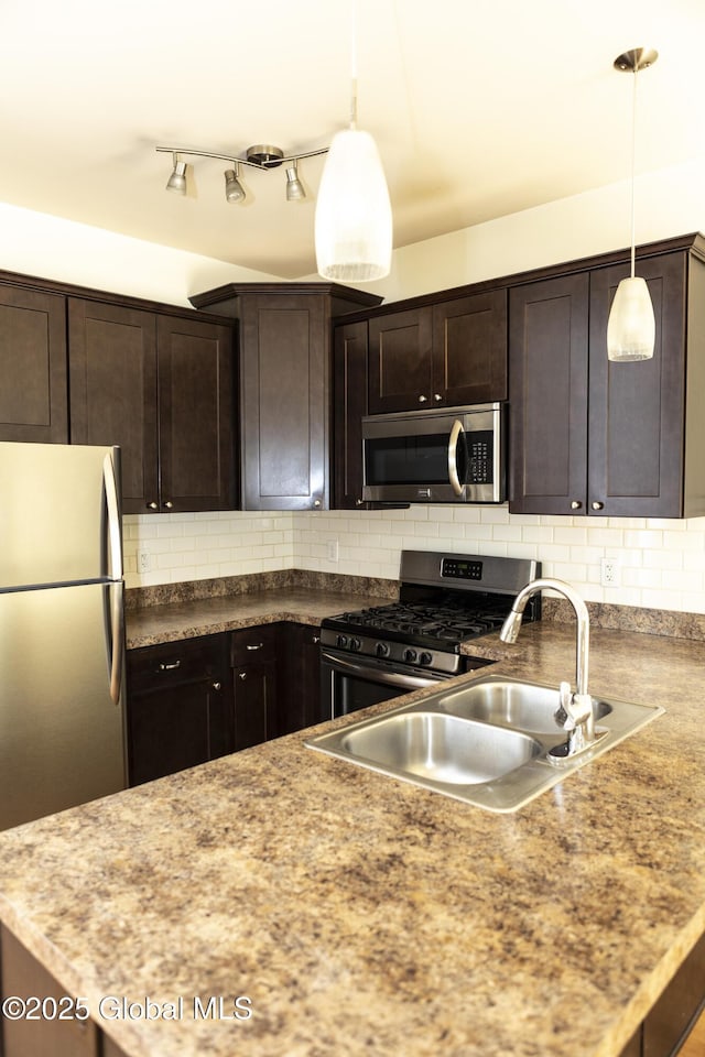 kitchen featuring appliances with stainless steel finishes, dark brown cabinets, a sink, hanging light fixtures, and decorative backsplash