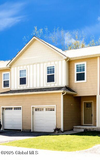 view of front of property featuring a garage, board and batten siding, asphalt driveway, and a front lawn