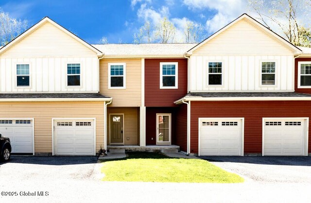 townhome / multi-family property with a garage, board and batten siding, driveway, and a front yard