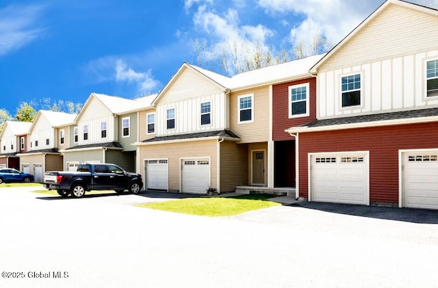 view of property featuring board and batten siding, an attached garage, a residential view, and driveway