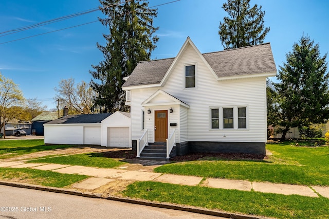 view of front of home featuring roof with shingles, a detached garage, a front lawn, and an outdoor structure