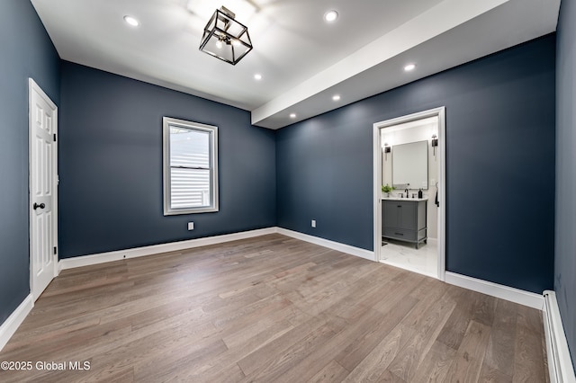empty room with baseboard heating, recessed lighting, wood finished floors, and baseboards