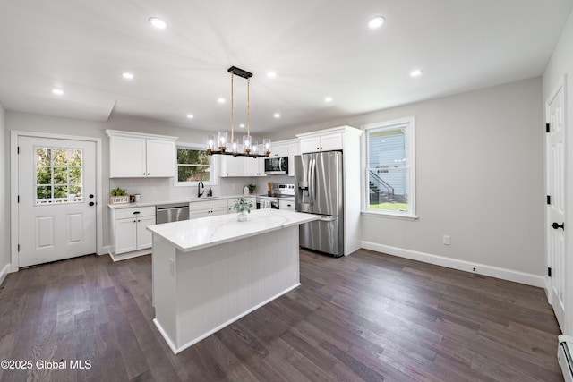 kitchen featuring white cabinets, a sink, stainless steel appliances, a baseboard heating unit, and a center island