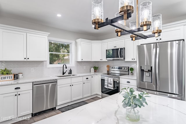 kitchen featuring a notable chandelier, a sink, white cabinets, and stainless steel appliances