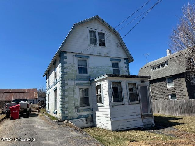 rear view of house featuring fence and a gambrel roof