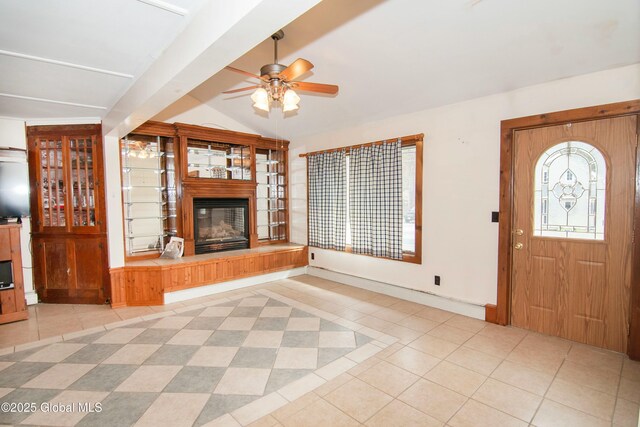 unfurnished living room featuring tile patterned floors, a glass covered fireplace, a ceiling fan, baseboards, and lofted ceiling