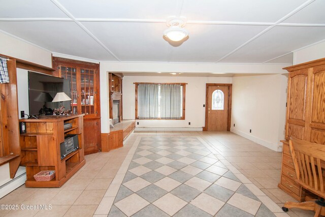unfurnished living room with baseboards, light tile patterned floors, and a baseboard radiator