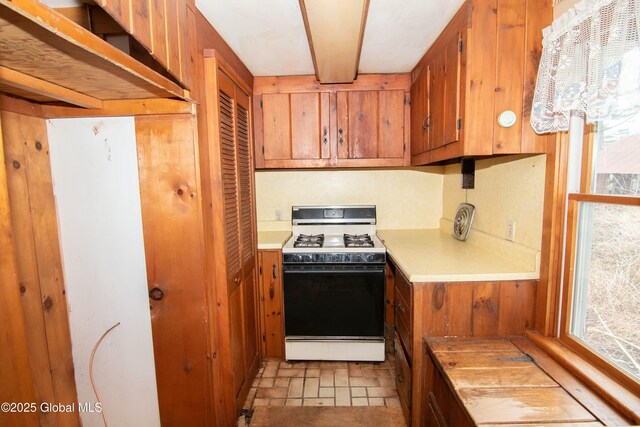 kitchen featuring light countertops, brown cabinets, and range with gas cooktop