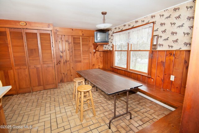 dining room with a wainscoted wall, brick patterned floor, and wood walls