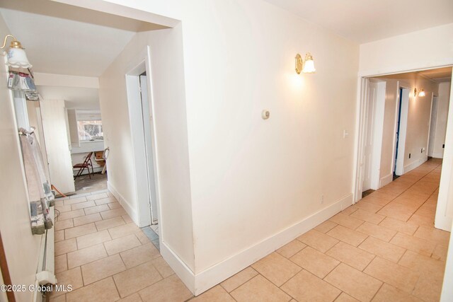 hall with light tile patterned flooring and baseboards