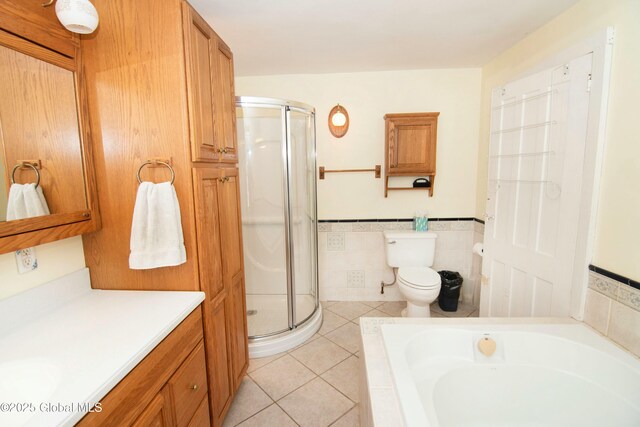 bathroom with toilet, tile patterned floors, a shower stall, and a garden tub