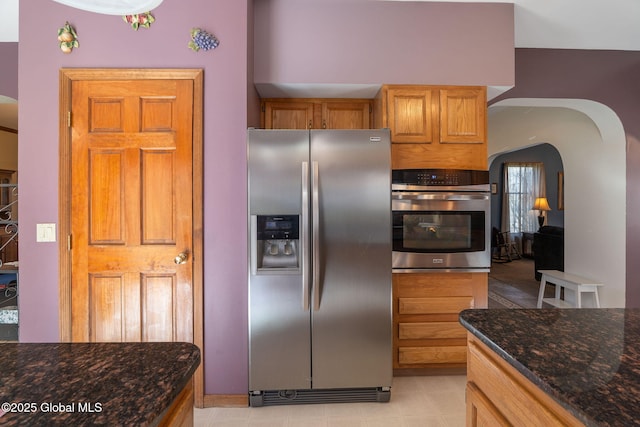 230 Zicha Rd, Esperance, NY 12092 - kitchen with brown cabinetry, arched walkways, dark stone countertops, and stainless steel appliances
