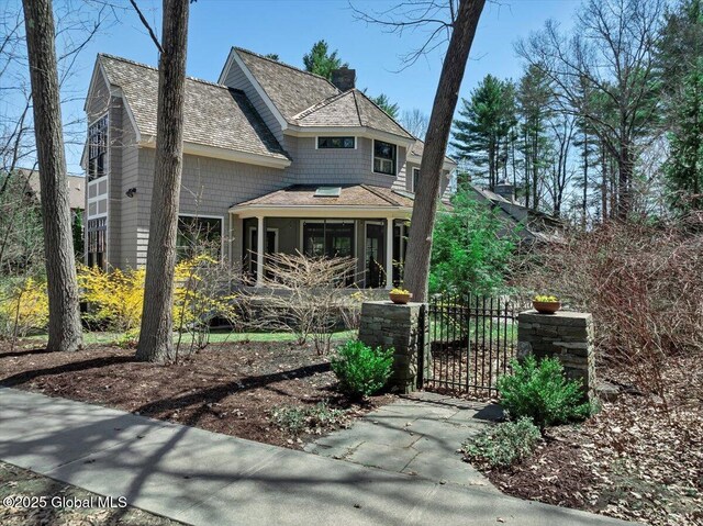 1 Joshua Rd, Saratoga Springs, NY 12866 - view of front of house featuring a gate, a chimney, a shingled roof, fence, and a sunroom