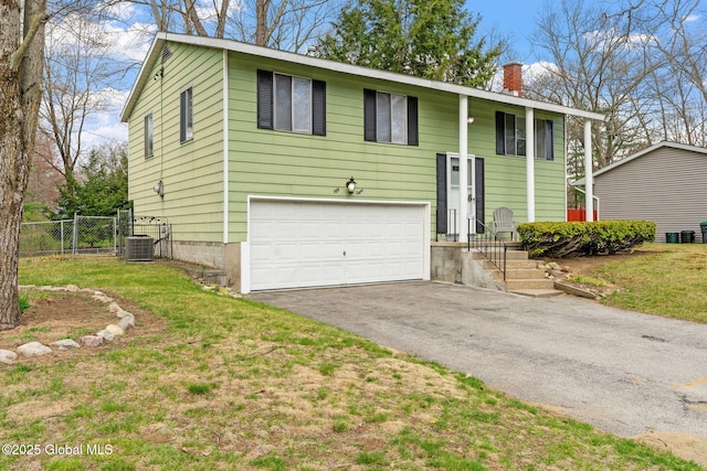 raised ranch featuring a garage, fence, cooling unit, a chimney, and driveway