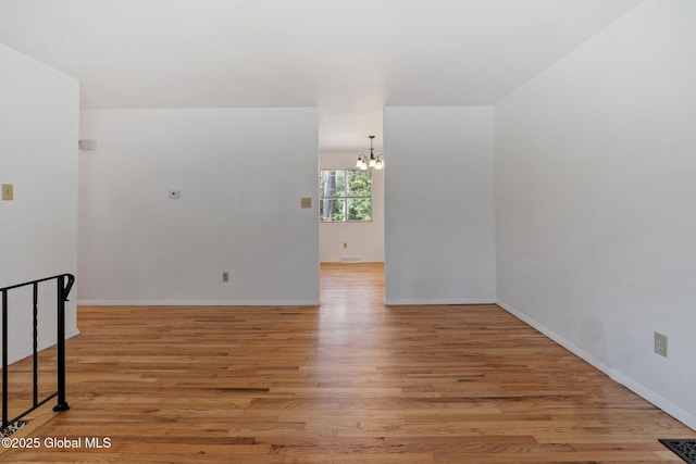 empty room with visible vents, baseboards, a chandelier, and light wood finished floors