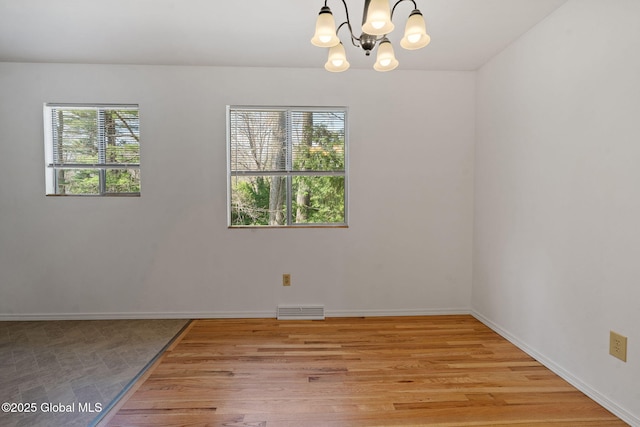 empty room featuring baseboards, plenty of natural light, visible vents, and a notable chandelier