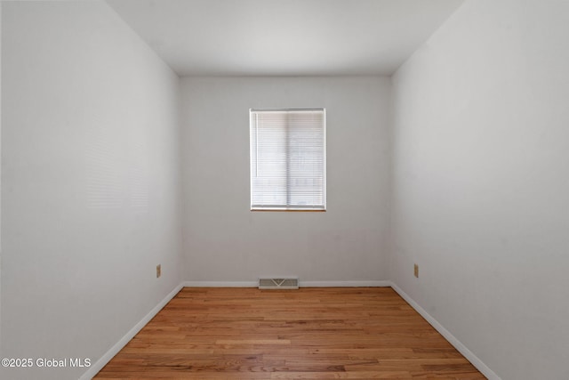 unfurnished room featuring visible vents, light wood-style flooring, and baseboards