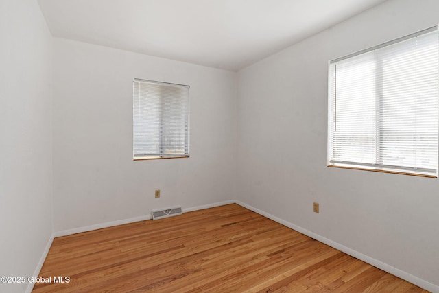 empty room featuring baseboards, light wood-style flooring, and visible vents