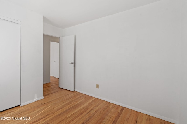 unfurnished bedroom featuring baseboards, light wood finished floors, and a closet