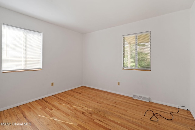 empty room featuring baseboards, light wood-type flooring, and visible vents