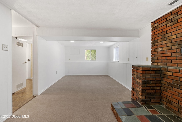 below grade area with visible vents, carpet, and brick wall
