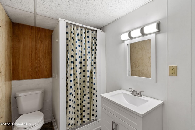 bathroom featuring vanity, toilet, a paneled ceiling, and a stall shower