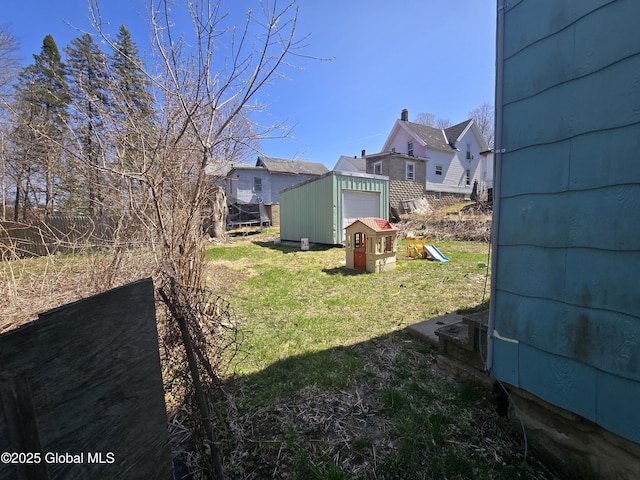 view of yard with fence, an outdoor structure, and a detached garage