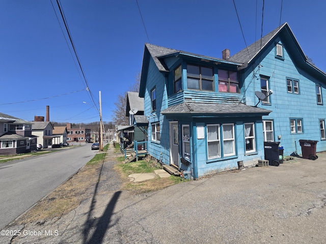 exterior space with a chimney, roof with shingles, and a residential view