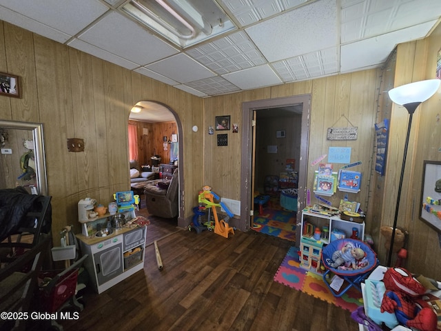 game room featuring arched walkways, wood walls, and wood finished floors