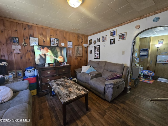living room with wooden walls, wood finished floors, and arched walkways