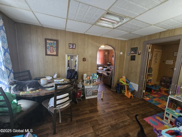 dining room featuring arched walkways, wood finished floors, and wooden walls