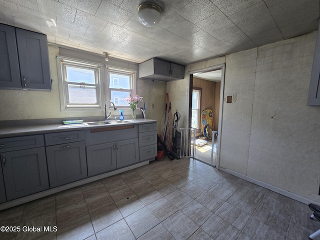 kitchen featuring gray cabinetry, a sink, and light countertops