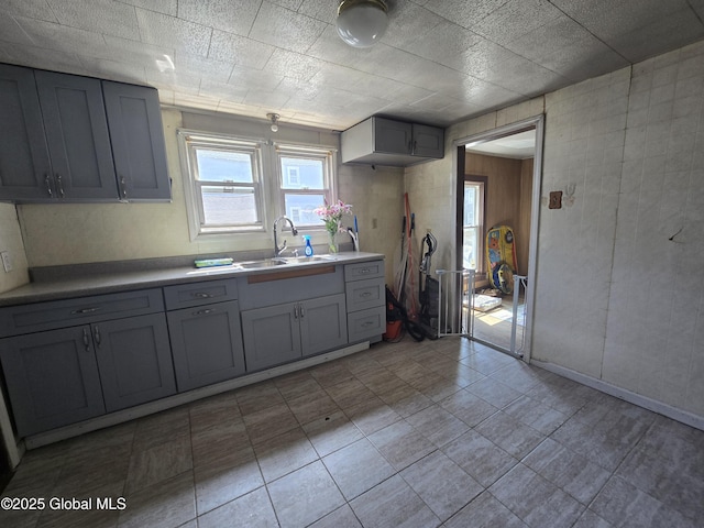 kitchen featuring light countertops, gray cabinets, and a sink