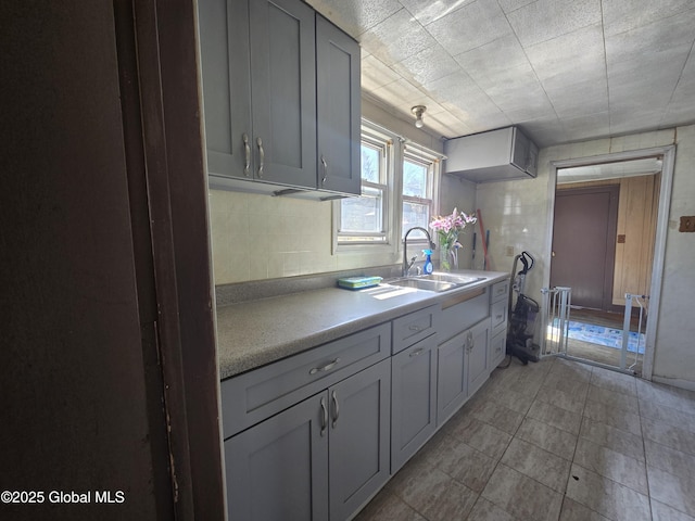 kitchen with light countertops, light tile patterned flooring, a sink, and tasteful backsplash