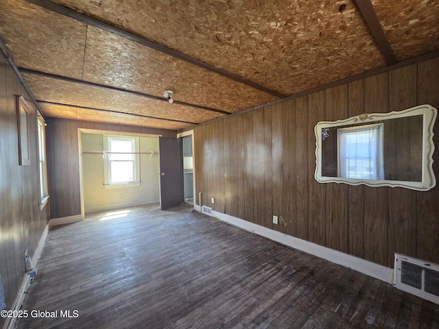 spare room featuring visible vents, wood walls, and dark wood-style floors