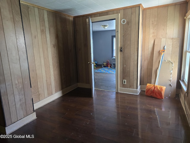 spare room with wood-type flooring, wood walls, and baseboards