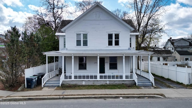 farmhouse-style home with a porch and fence