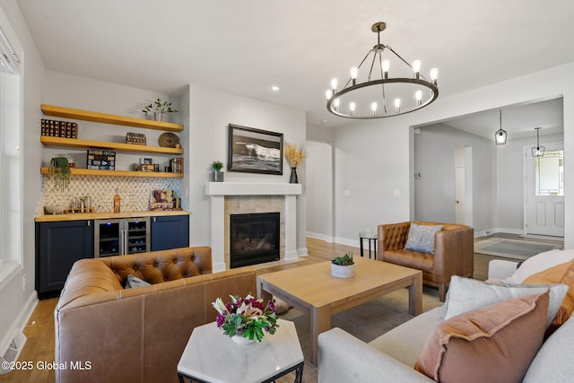 6 Gorsline Dr, Halfmoon, NY 12118 - living area featuring light wood finished floors, wine cooler, wet bar, a tiled fireplace, and a notable chandelier