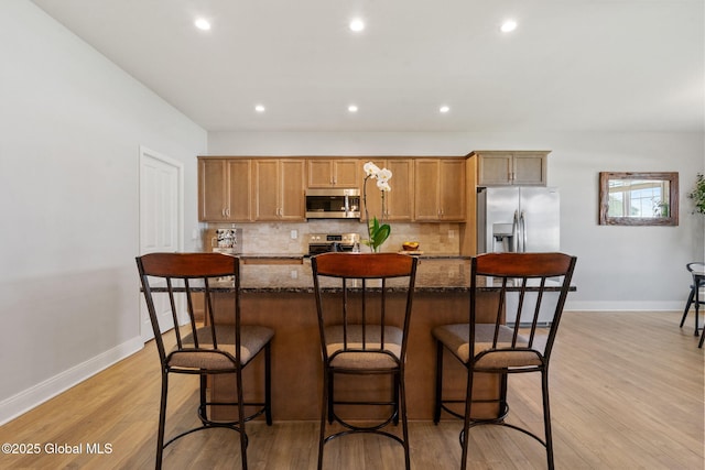6 Gorsline Dr, Halfmoon, NY 12118 - kitchen with dark stone countertops, stainless steel appliances, light wood-style flooring, backsplash, and a kitchen island